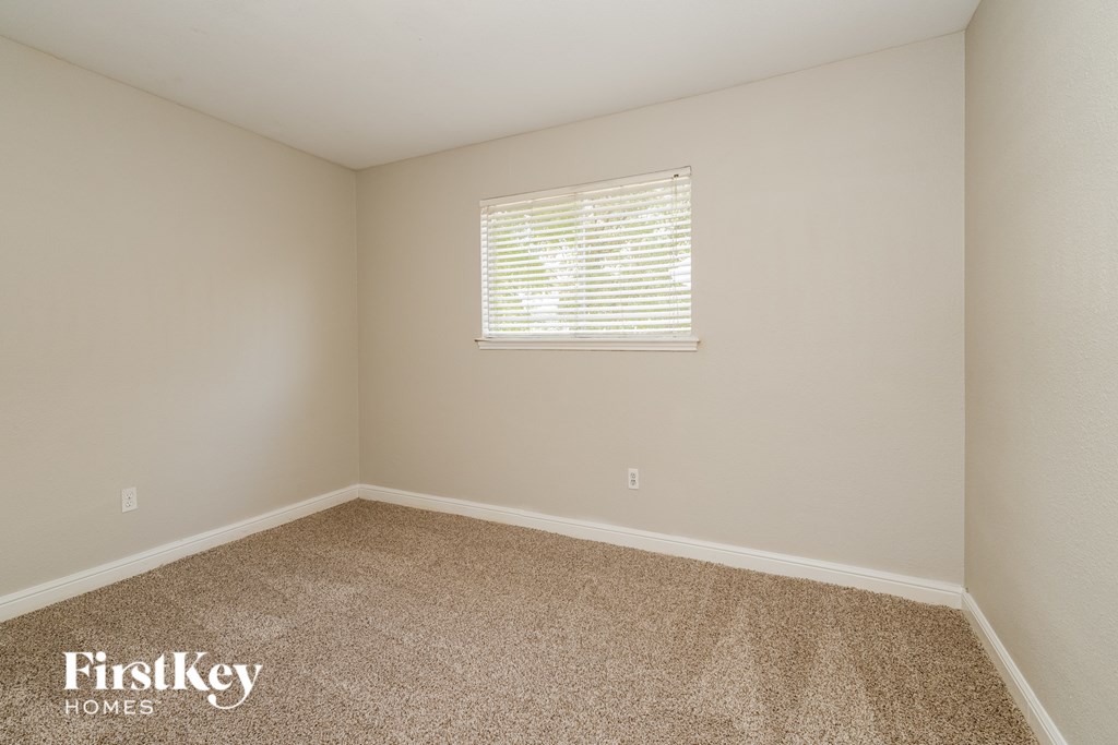 A room with a carpeted floor and a window with blinds.