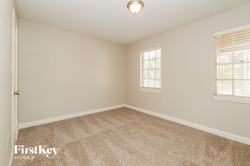 A room with a carpeted floor and a window with blinds.