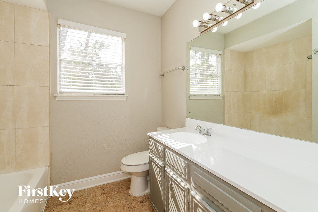 A bathroom with a toilet, sink, and a mirror.