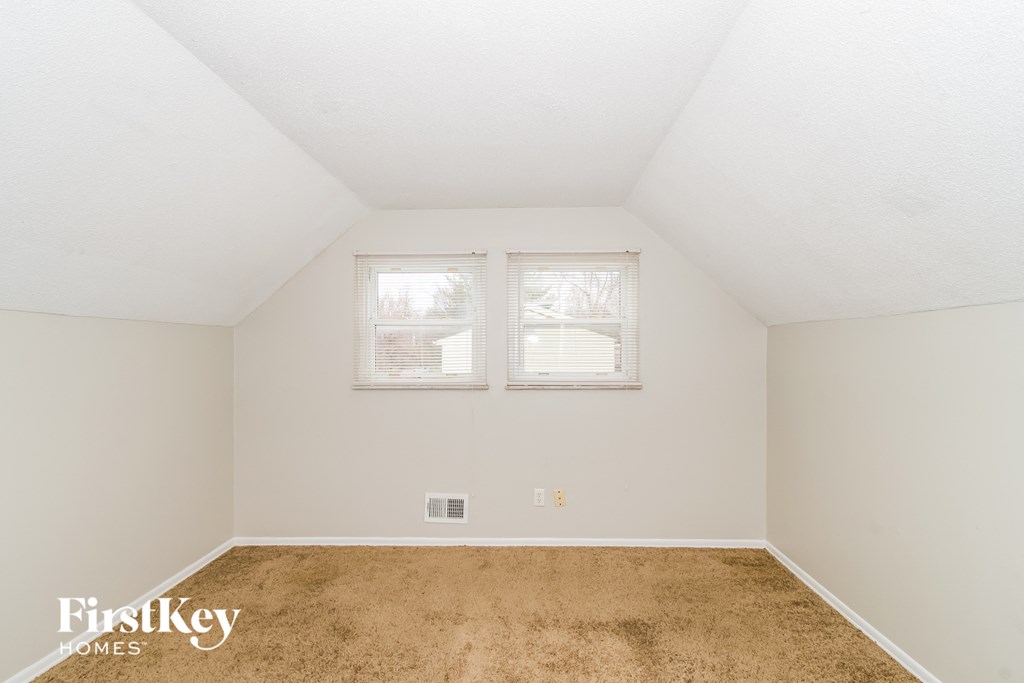 a bedroom with carpet and two windows