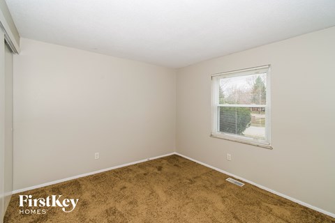 the living room of a small white house with brown carpet and a window