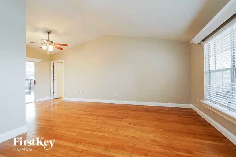 an empty living room with wood floors and a ceiling fan