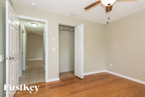a bedroom with a ceiling fan and a hallway with a closet