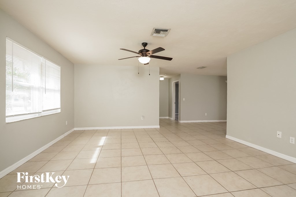 an empty living room with a ceiling fan and tiled floor
