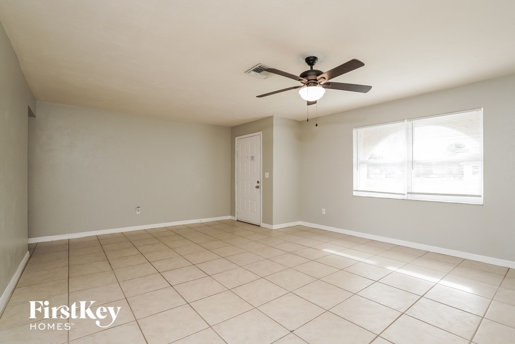 an empty living room with a ceiling fan and tiled floors