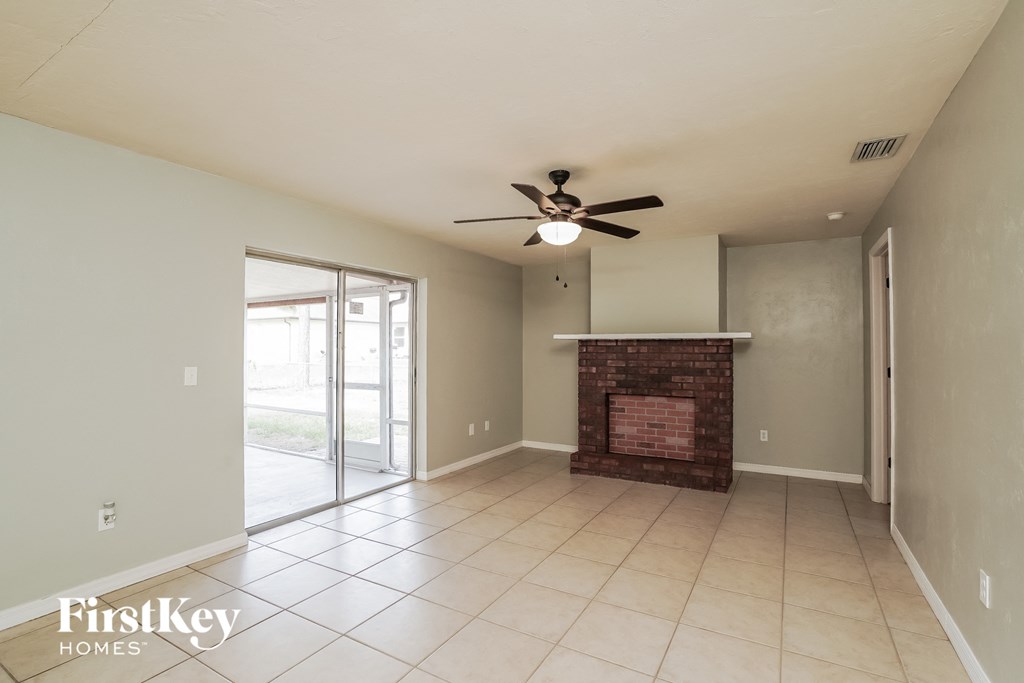 an empty living room with a fireplace and a ceiling fan