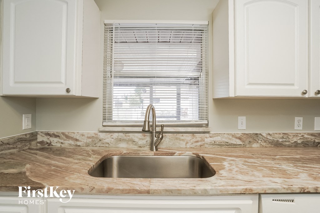 a kitchen with white cabinets and a sink and a window