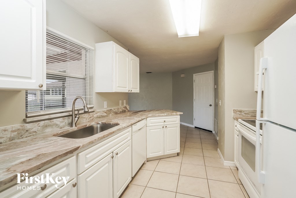 a kitchen with white cabinets and a sink and a window