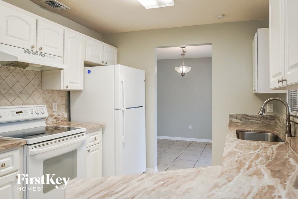 a kitchen with white cabinets and appliances and a white refrigerator