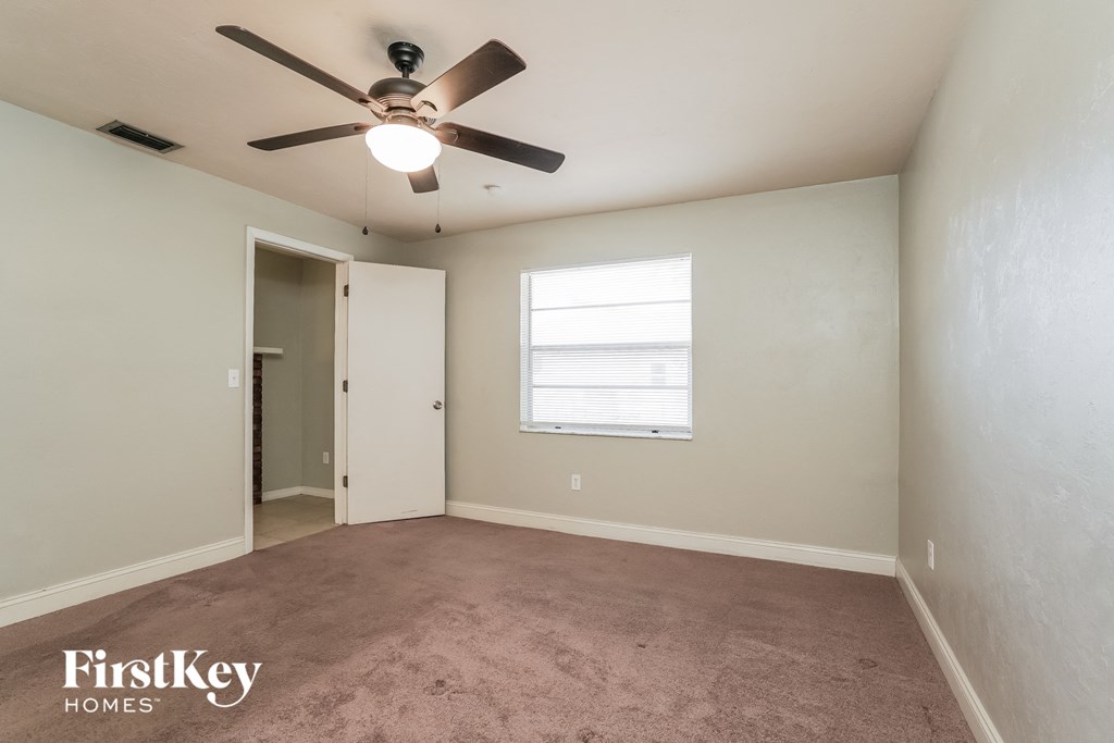 a carpeted room with a ceiling fan and a window