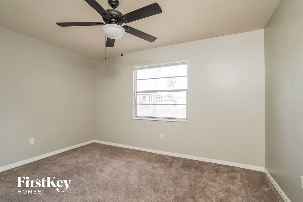 a carpeted room with a ceiling fan and a window