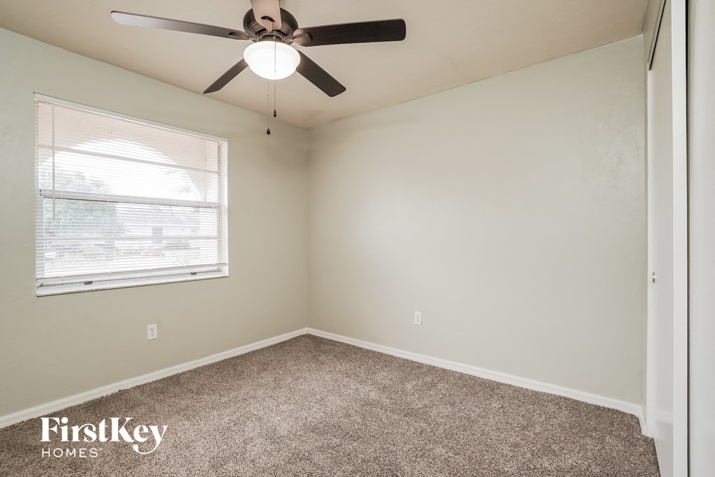 an empty room with a ceiling fan and a window