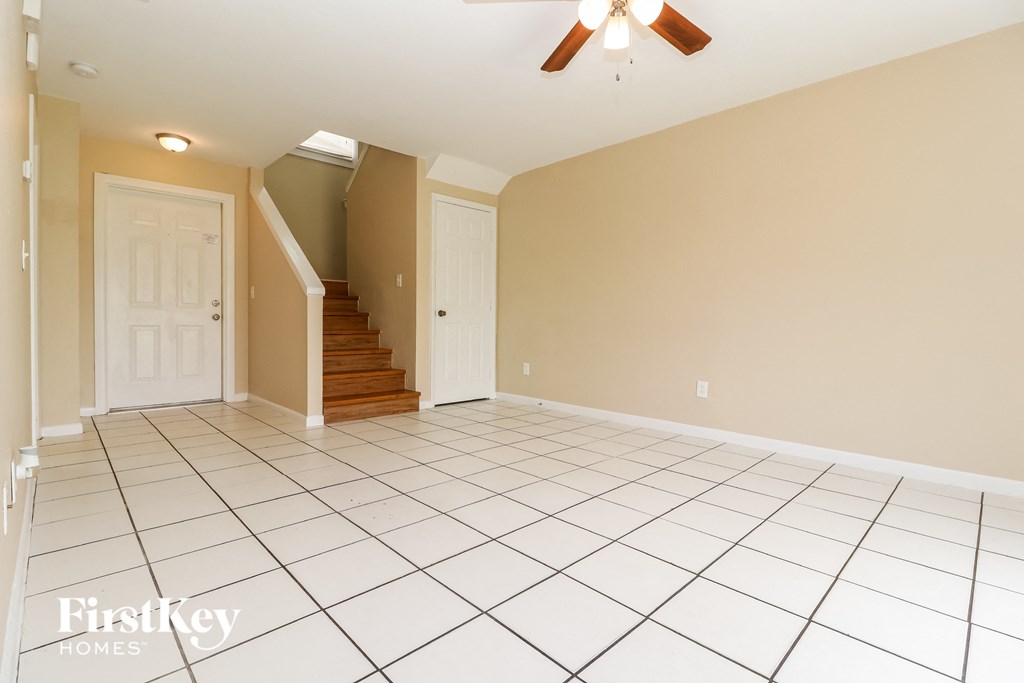 A spacious room with a staircase and a ceiling fan.