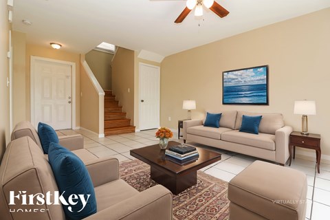 A living room with a couch, a coffee table, and a painting of a beach scene on the wall.
