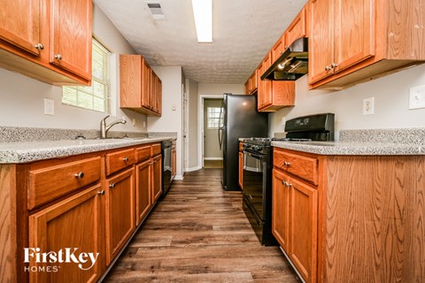 A kitchen with wooden cabinets and a black refrigerator.