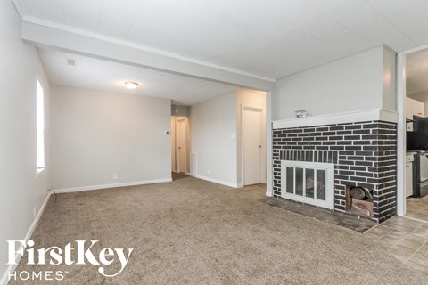 A living room with a fireplace and a kitchen area in the background.