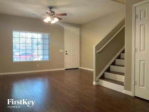 A spacious room with wooden floors and a staircase leading to another level.