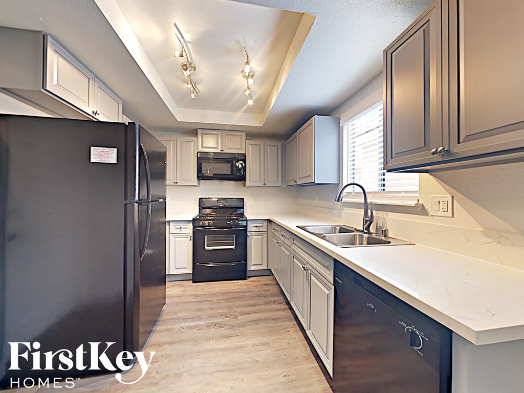 A kitchen with a refrigerator, oven, and sink.