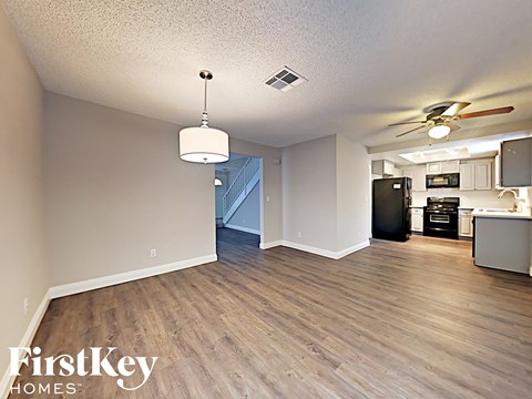 A well lit kitchen with a black fridge and a wooden floor.
