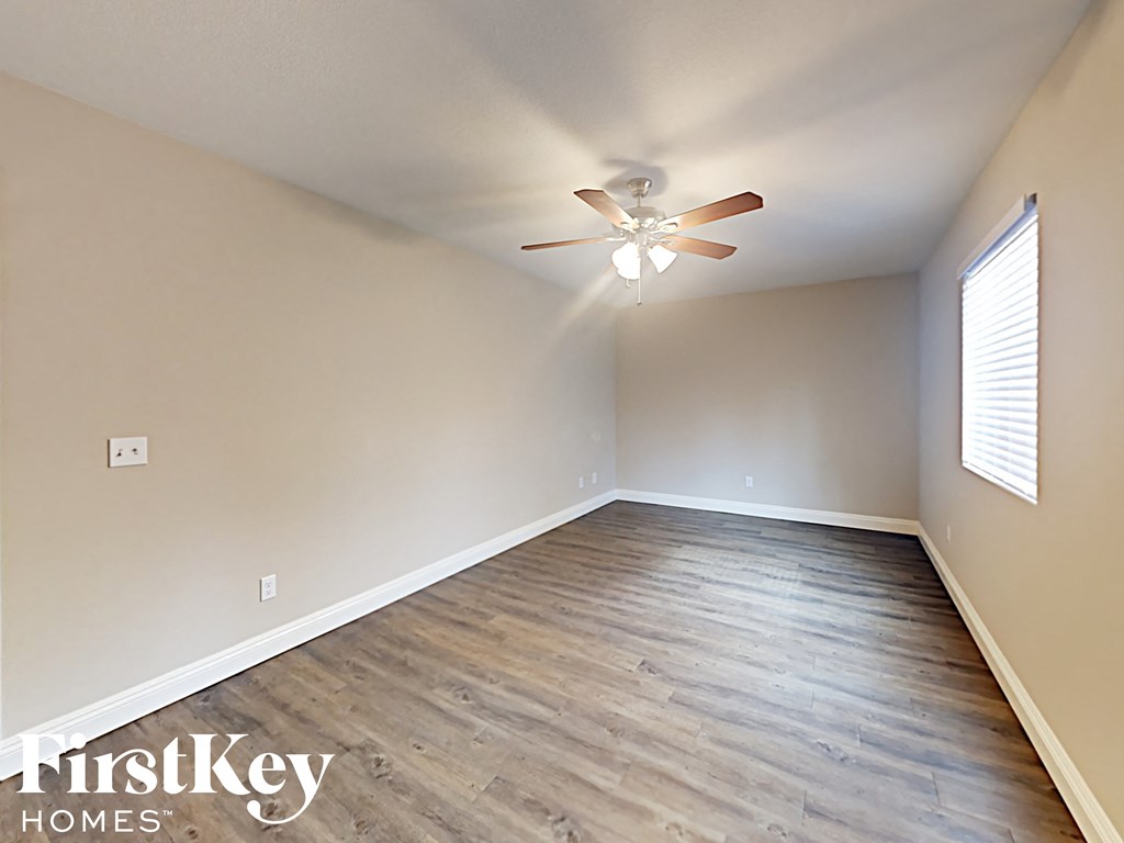A spacious room with a ceiling fan and wooden flooring.