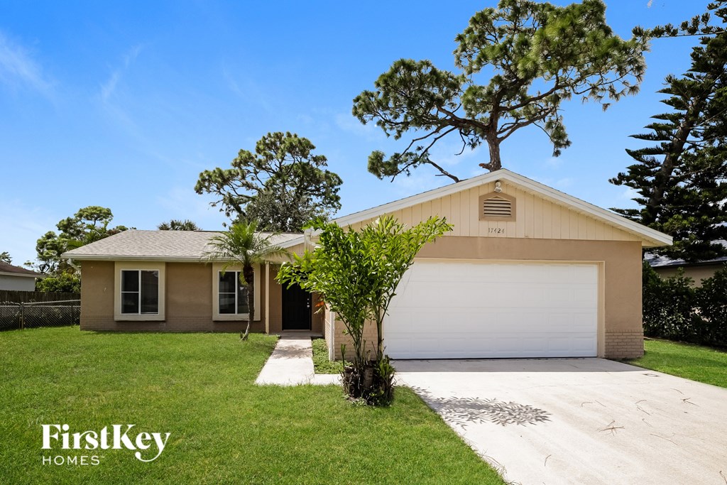 A house with a garage and a tree on top of it.