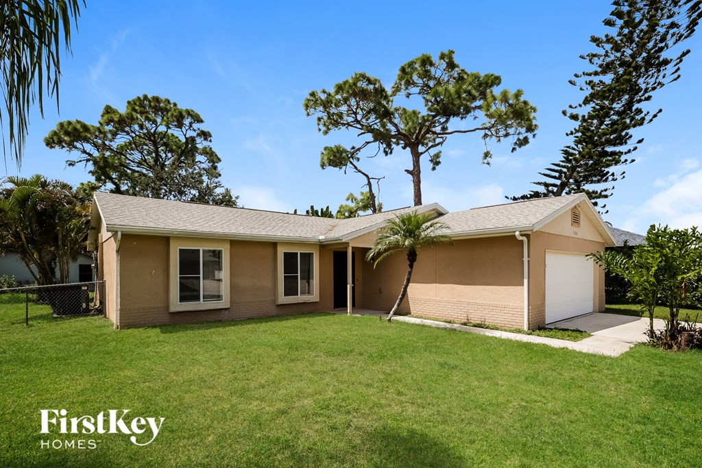 A house with a garage and a tree in front of it.