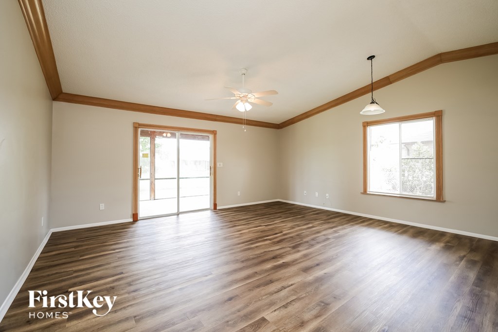 A spacious room with wooden floors and a ceiling fan.