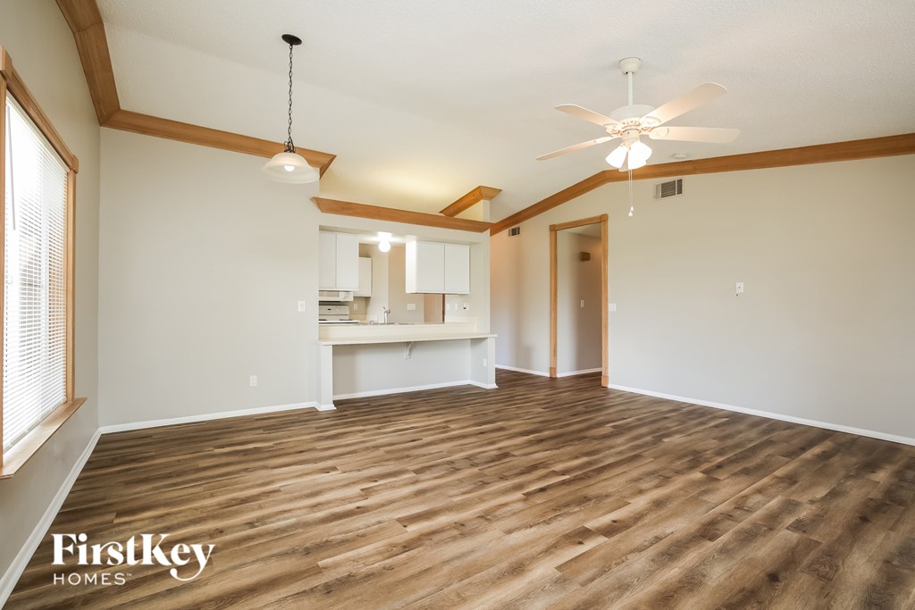 A spacious room with wooden flooring and a ceiling fan.