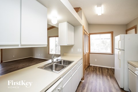 A kitchen with white cabinets and a wooden floor.