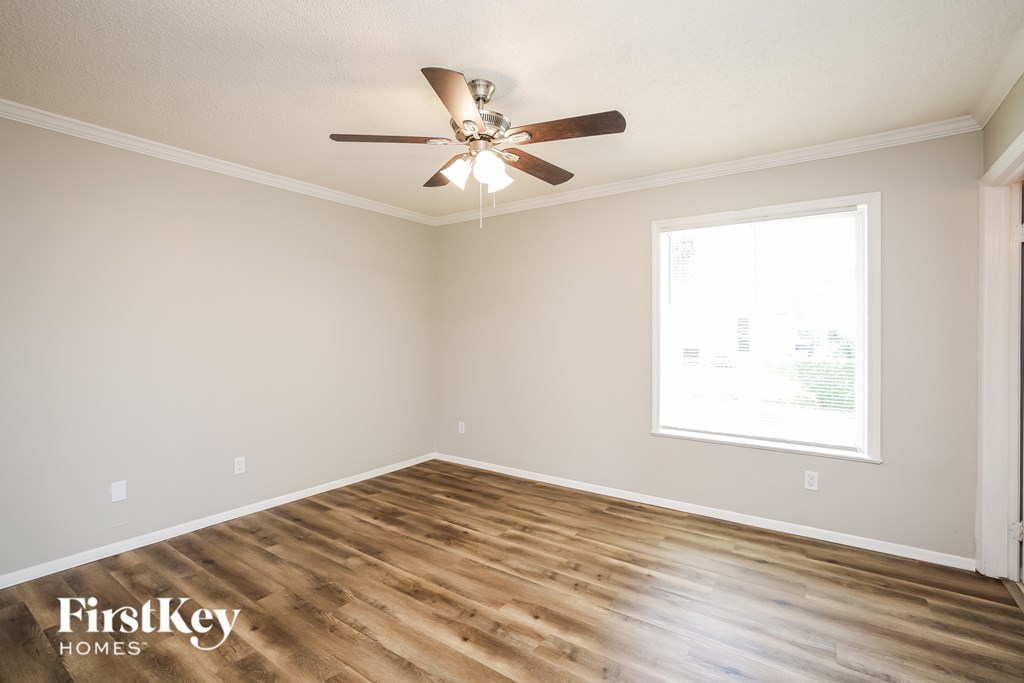 A room with a ceiling fan and wooden flooring.