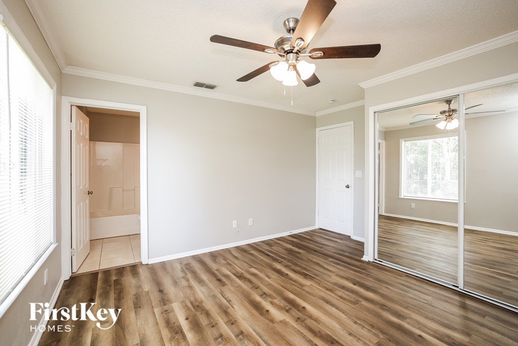 A room with a ceiling fan and wooden flooring.