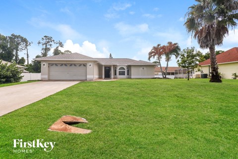 a large lawn in front of a house with palm trees