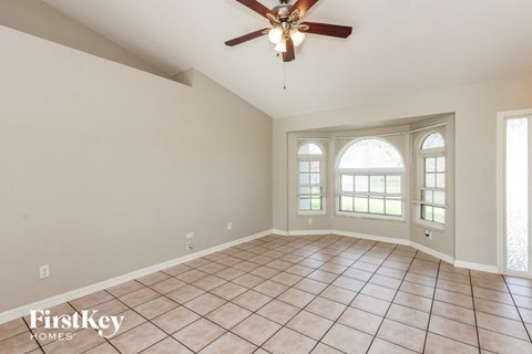 an empty living room with a ceiling fan and a window