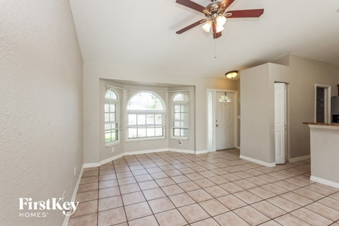 an empty living room with a ceiling fan and a window