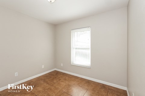 the living room of a home with a tiled floor and a window