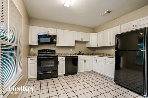 a kitchen with white cabinets and black appliances