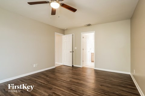 the spacious living room with hardwood flooring and a ceiling fan