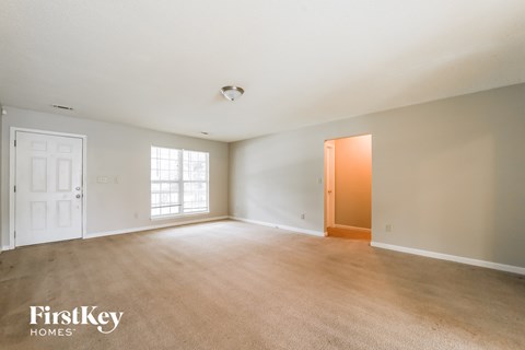 an empty living room with a door to a hallway and a window