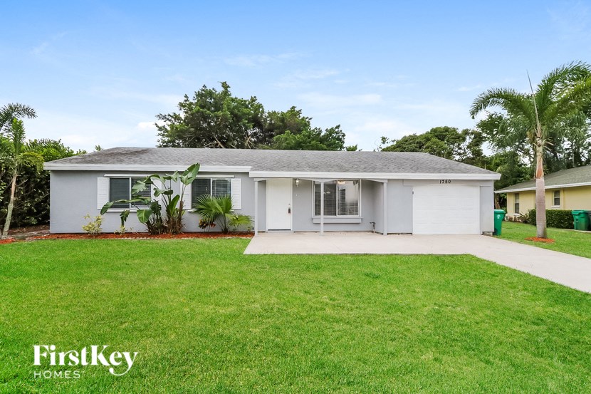 a white house with a lawn and palm trees