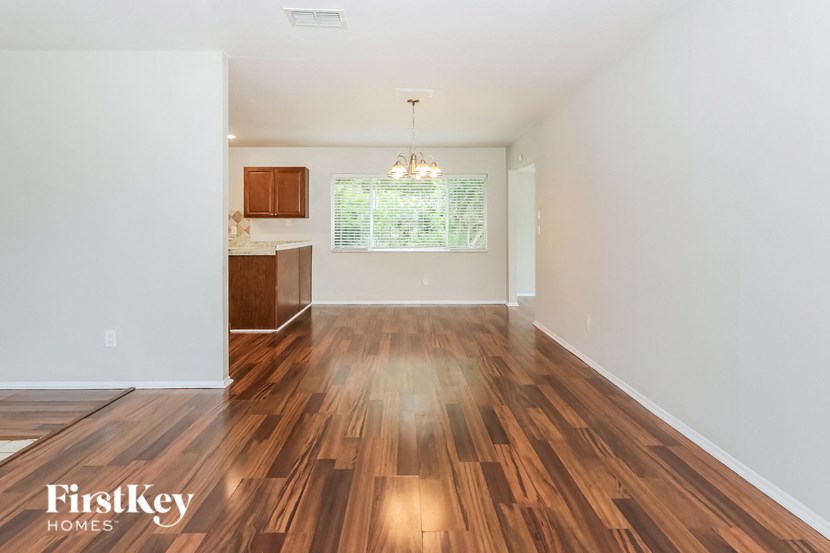 the living room and kitchen of an empty house with wood flooring