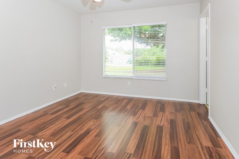 the living room of an apartment with wood flooring and a window