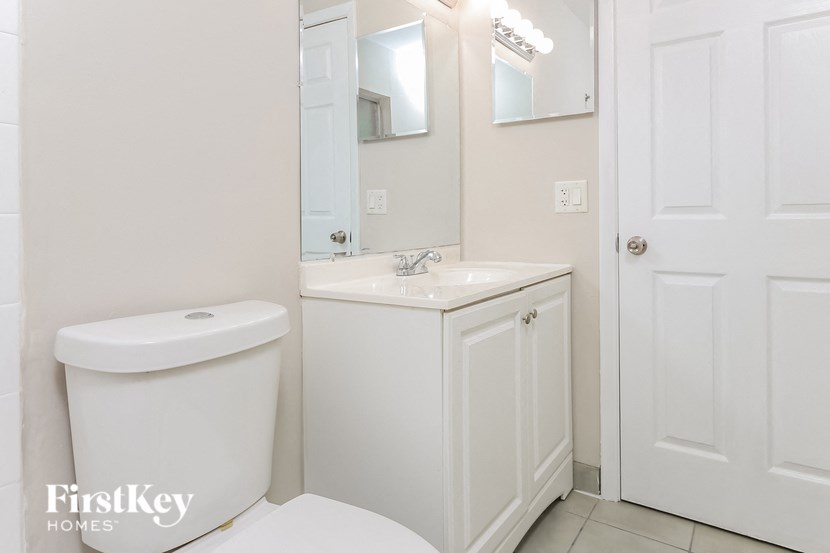 a white bathroom with a sink and toilet and a mirror