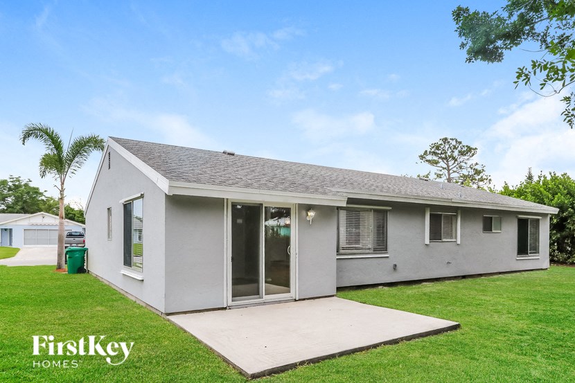 a small white house with a lawn and a driveway