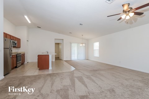A spacious living room with a kitchen area in the background and a rug on the floor.