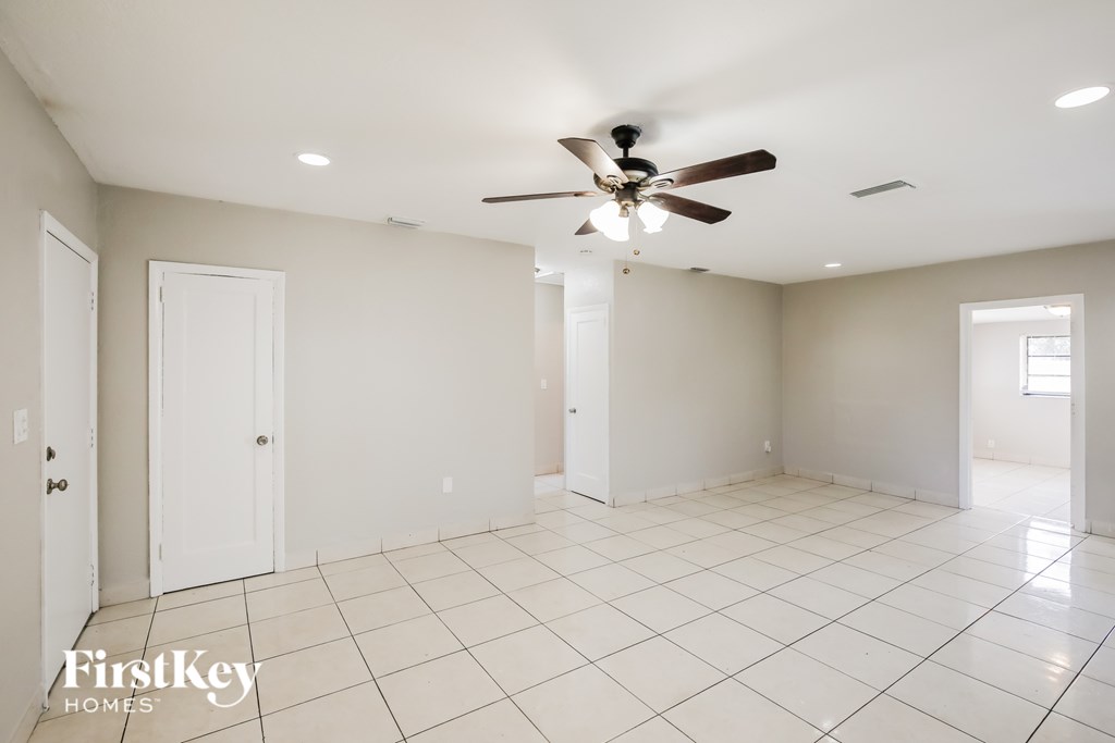 A spacious room with a ceiling fan and white tile flooring.