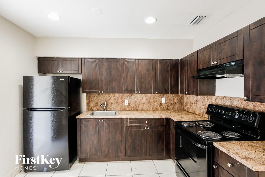 A kitchen with dark wood cabinets and black appliances.