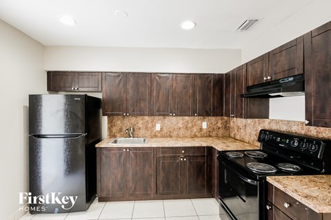 A kitchen with dark wood cabinets and black appliances.