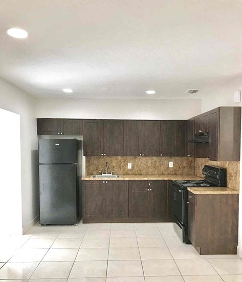 A kitchen with brown cabinets and black appliances.