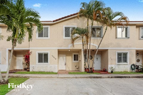a beige house with palm trees in front of it