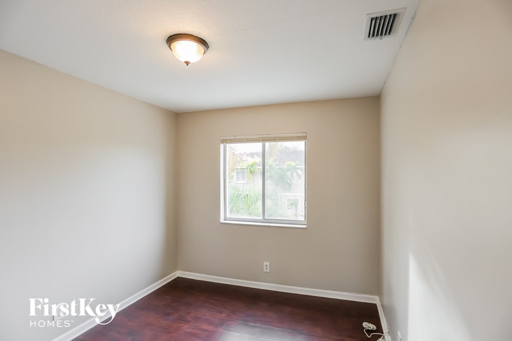 a empty room with a window and wooden floors